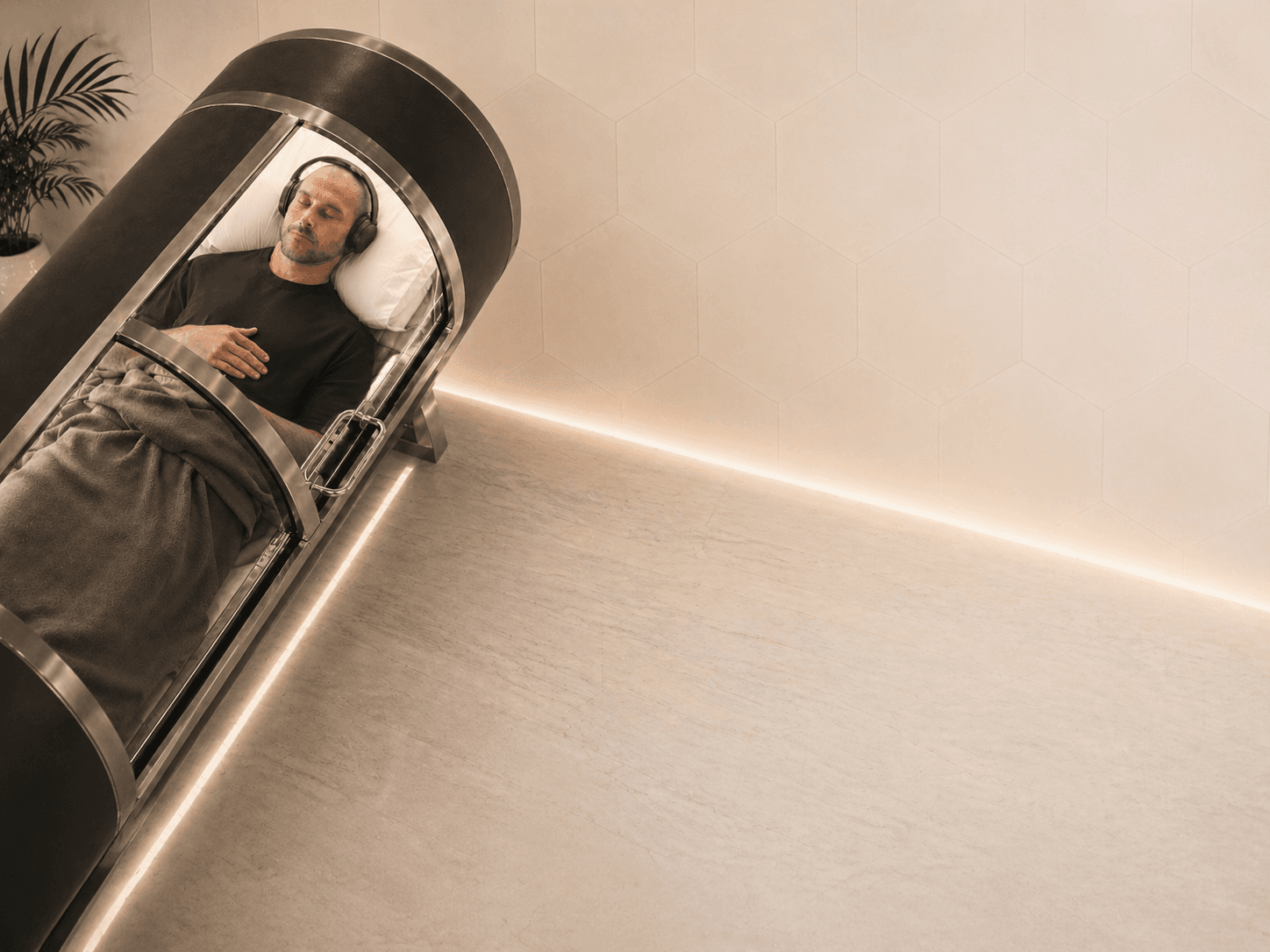 A client resting with headphones on inside the AirPod hyperbaric chamber at Le Chalet Clinic